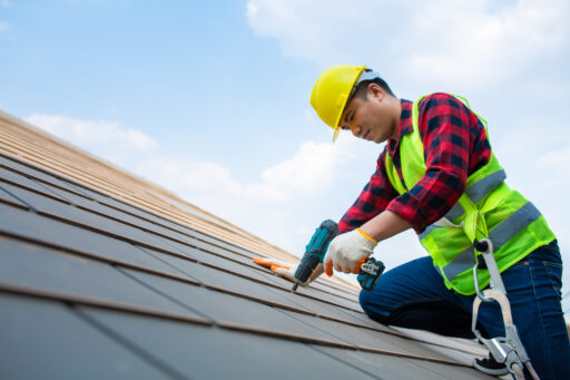 A roofer in safety gear works to repair a commercial roof.