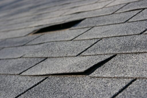 A close-up image of a shingle roof that has impact damage and missing shingles.