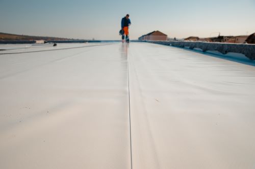 A flat roofing system with a technician in the background.